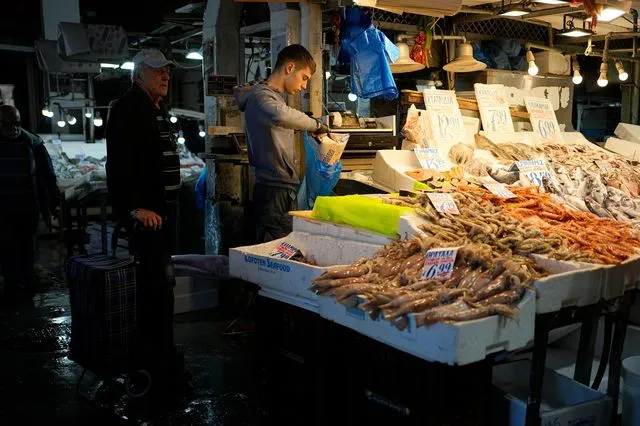 Ιχθυοπώλης τυλίγει ψάρια για έναν πελάτη στην Βαρβάκειο