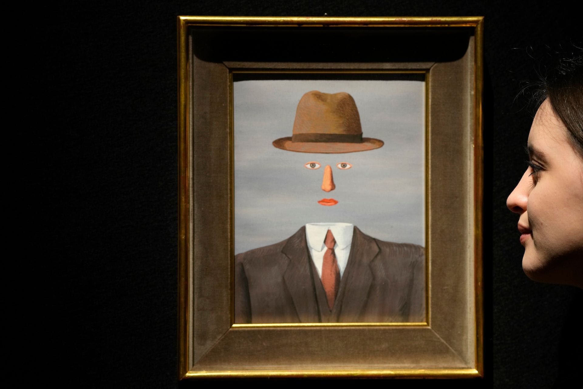 A woman views a painting by Rene Magritte called Le Paysage de Baucis as it is displayed at Christie's auction rooms in London, Friday, March 1, 2024. The painting estimated at 2.4-3 million UK Pounds (3.1-3.8 million US Dollars) will be for auction in the The 20th / 21st Century: London Evening Sale and The Art of the Surreal Evening Sale on March 7. 