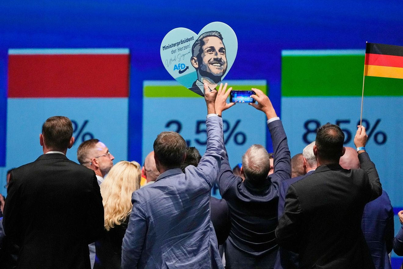 Μέλη του κόμματος πανηγυρίζουν κρατώντας μια αφίσα του επικεφαλής υποψηφίου του AfD, Ulrich Siegmund